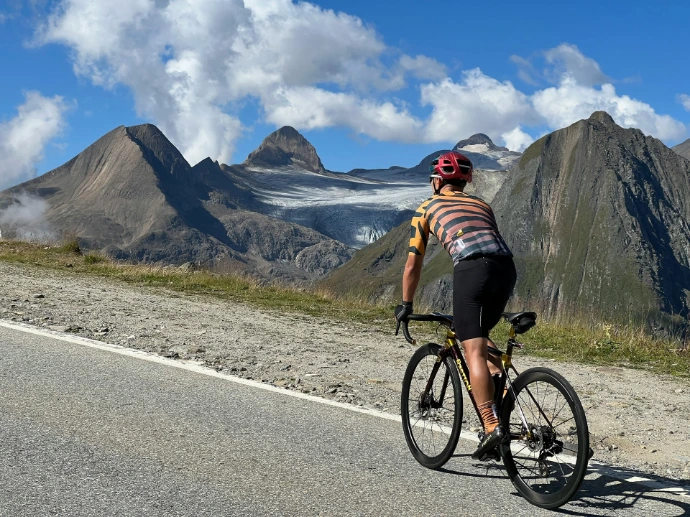Cyclist on a mountain road with glaciers behind